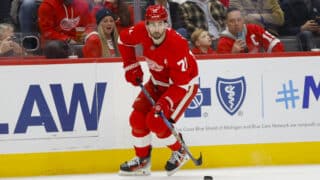Dylan Larkin pelaamassa Detroit Red Wingsin paidassa helmikuussa. Kapteeni kuljettaa kiekkoa oikealla laidalla, katse ylhäällä.