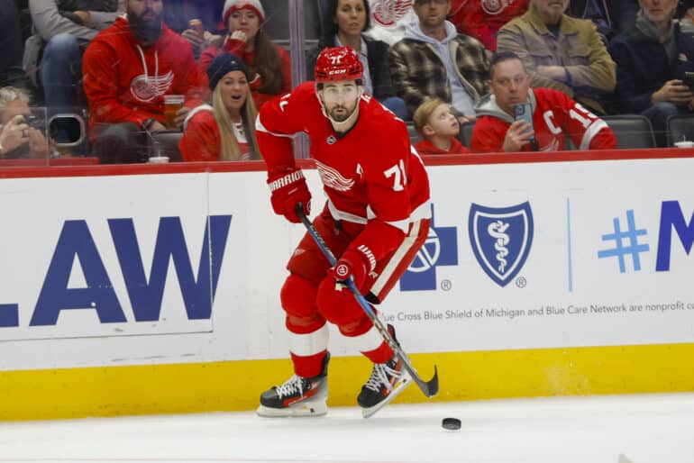 Dylan Larkin pelaamassa Detroit Red Wingsin paidassa helmikuussa. Kapteeni kuljettaa kiekkoa oikealla laidalla, katse ylhäällä.